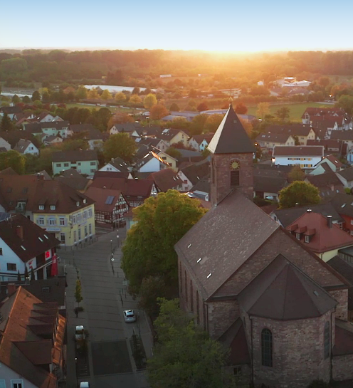 image title Luftaufnahme von Iffezheim bei Sonnenuntergang, die warmen Farben des Himmels spiegeln sich in den Gebäuden wider.